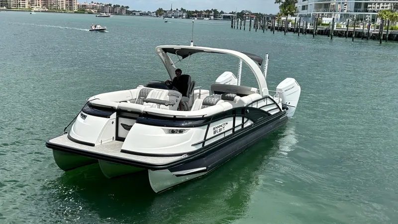 Slide: The Image of 2024 Bennington QX Line pontoon boat cruising on a scenic waterway. - 23