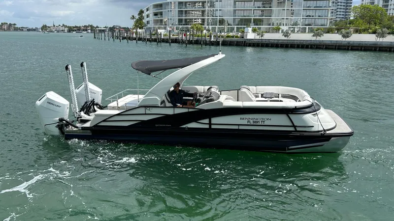 Slide: The Image of 2024 Bennington QX Line boat cruising on water near modern waterfront buildings. - 8