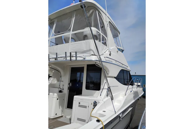 Slide: The Image of 2005 Silverton 38 Convertible yacht with enclosed flybridge, docked under clear skies. - 4