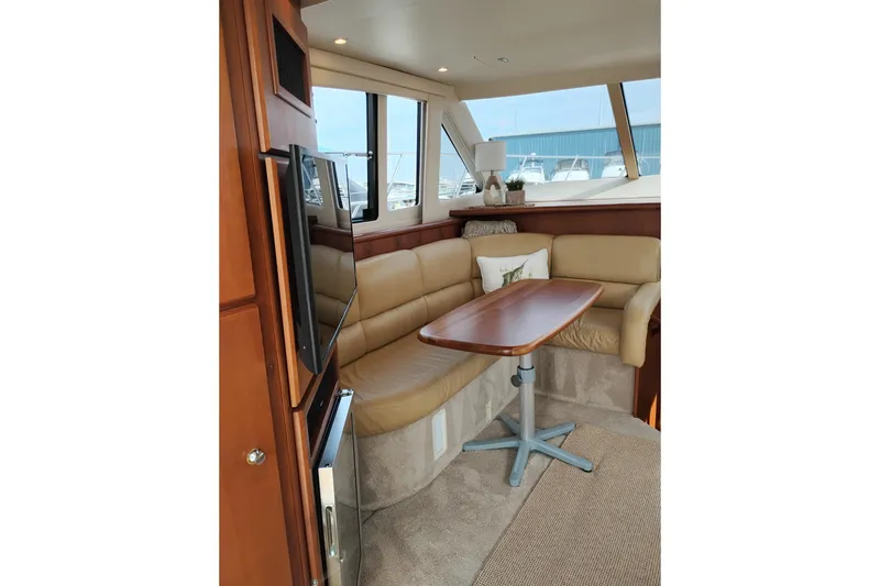 Slide: The Image of Interior of 2005 Silverton 38 Convertible yacht with beige seating and wooden table. - 49