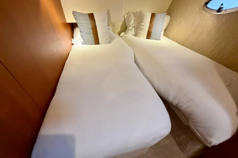 Slide: The Image of Twin beds in the 2005 Silverton 38 Convertible yacht cabin, featuring striped pillows. - 79