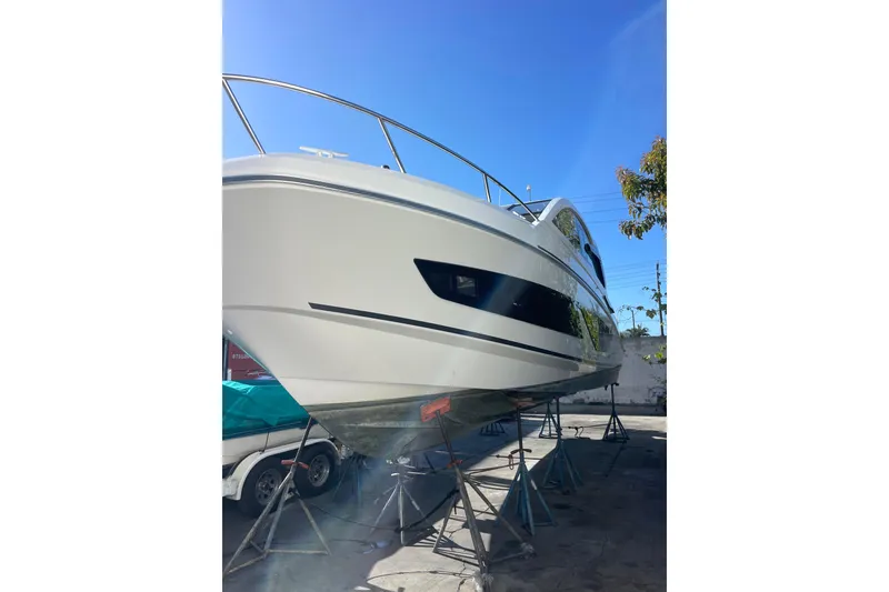 Slide: The Image of 2023 Beneteau Gran Turismo 32 yacht on stands, viewed from the front under a clear blue sky. - 2
