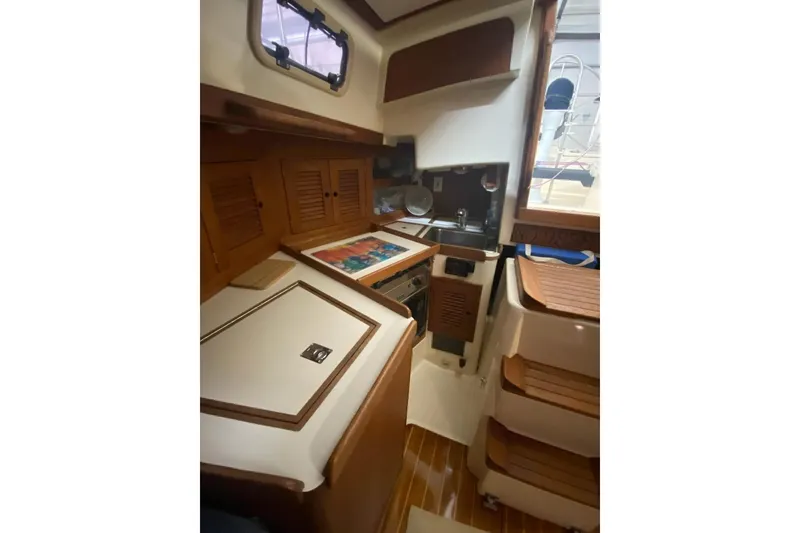 Slide: The Image of Interior of 1992 Tartan 31 Piper sailboat with wooden cabinetry and compact kitchen area. - 9
