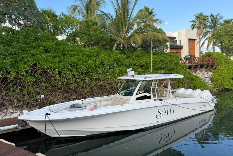 The Image of 2021 Boston Whaler 380 Outrage docked near lush greenery and modern architecture. - 0