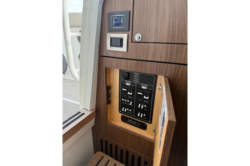 Slide: The Image of 2021 Boston Whaler 380 Outrage electrical panel with wood finish and control switches. - 14