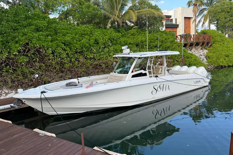 Slide: The Image of 2021 Boston Whaler 380 Outrage docked, surrounded by lush greenery and calm waters. - 2