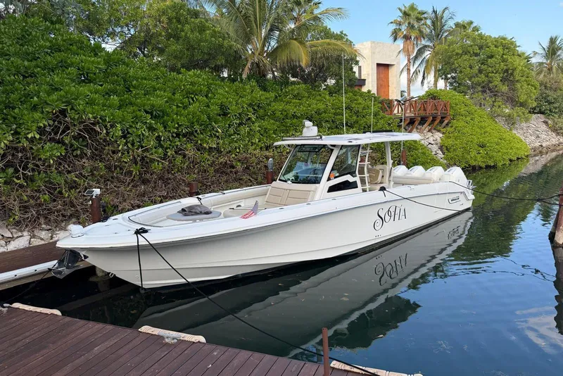 Slide: The Image of 2021 Boston Whaler 380 Outrage boat docked in a lush, tropical setting. - 4