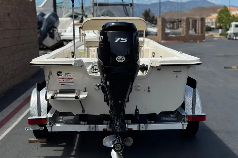 Slide: The Image of 2024 Carolina Skiff E18 JVX CC boat on trailer, featuring a 75 HP Suzuki outboard motor. - 4
