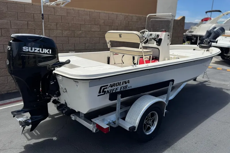 Slide: The Image of 2024 Carolina Skiff E18 JVX CC boat with Suzuki outboard motor on trailer. - 5