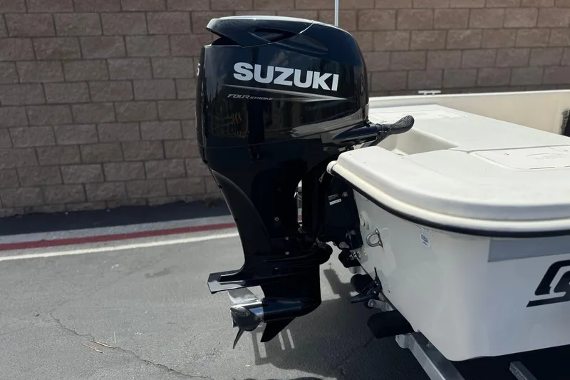 Slide: The Image of 2024 Carolina Skiff E18 JVX CC with Suzuki outboard motor, parked on pavement. - 6