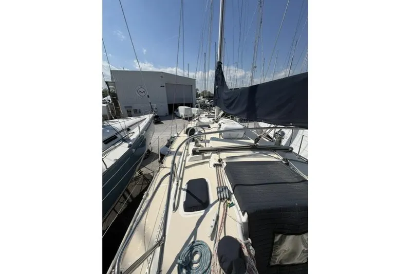 Slide: The Image of 2002 Saga 43 sailboat docked at marina, showcasing deck and rigging under clear sky. - 15