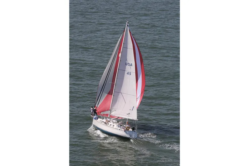 Slide: The Image of Sailing yacht Saga 43 (2002) with red and white sails on open water. - 2