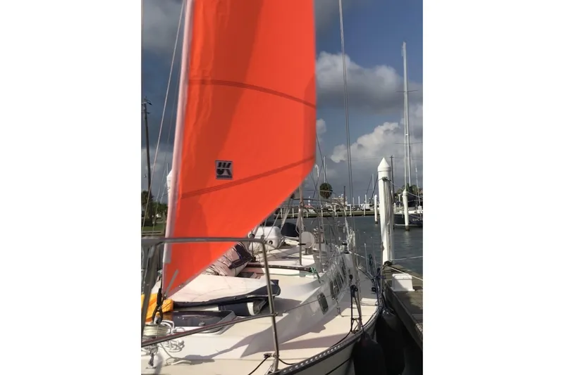 Slide: The Image of Sailboat Saga 43 (2002) with vibrant orange sail docked at marina. - 5