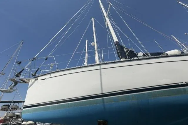 Slide: The Image of 2002 Saga 43 sailboat with white hull and blue bottom, docked under clear sky. - 8