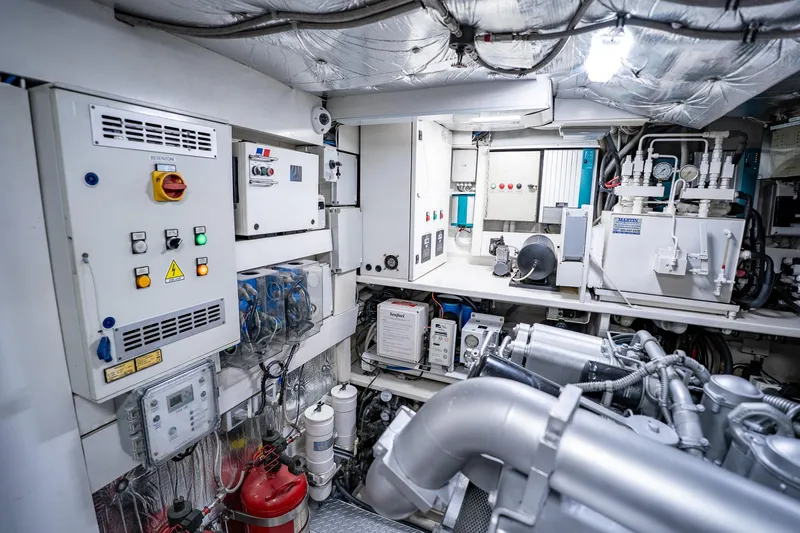 Slide: The Image of Engine room of a 2010 Pershing 80 yacht, showcasing complex machinery and control panels. - 102