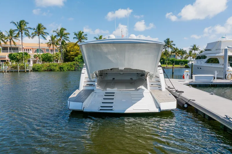 Slide: The Image of 2010 Pershing 80 yacht docked, rear view, with open garage, surrounded by palm trees. - 23