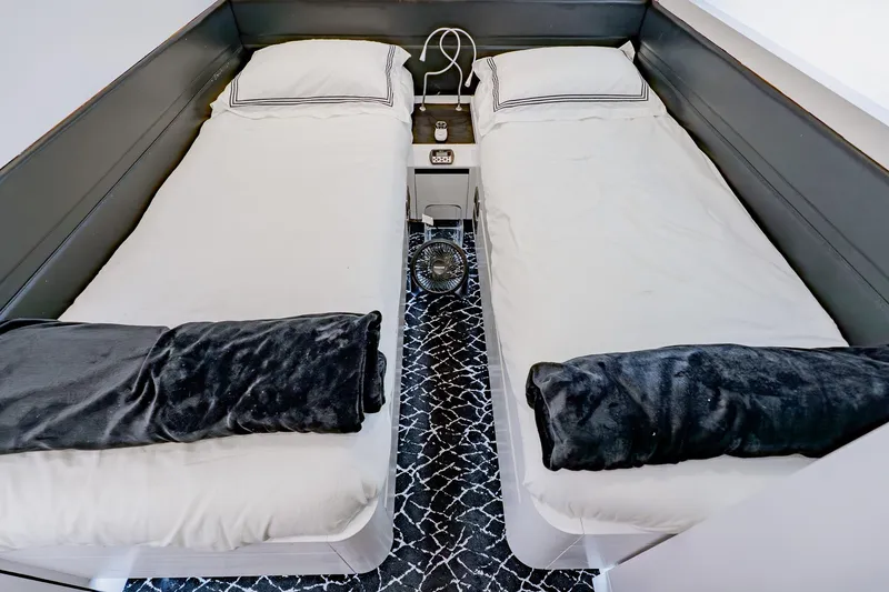 Slide: The Image of Twin beds in a 2010 Pershing 80 yacht cabin with modern decor and black accents. - 50