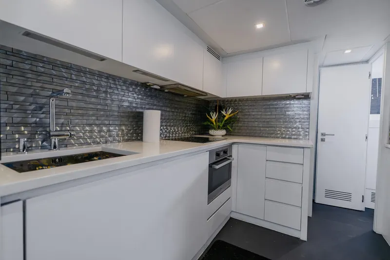 Slide: The Image of Modern kitchen interior on a 2010 Pershing 80 yacht, featuring sleek white cabinetry and metallic backsplash. - 84