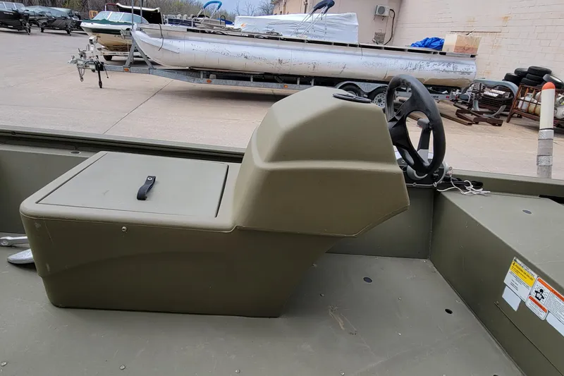 Slide: The Image of 2017 Tracker Grizzly 1648 SC boat interior with steering console, parked outdoors. - 9