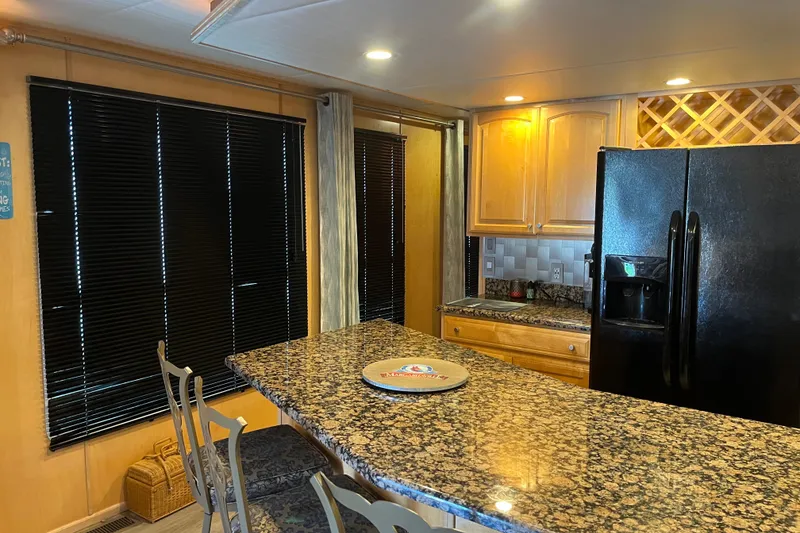 Slide: The Image of Kitchen interior with granite countertops, black refrigerator, and wooden cabinets in a 2005 Majestic Legacy. - 12