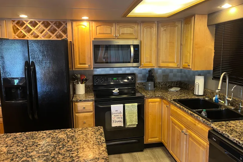 Slide: The Image of Modern kitchen with wooden cabinets, granite countertops, and black appliances, featuring a Majestic Legacy 2005 model. - 13