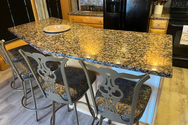 Slide: The Image of Luxurious kitchen with granite countertop, ornate bar stools, and modern appliances in a Majestic Legacy RV. - 14