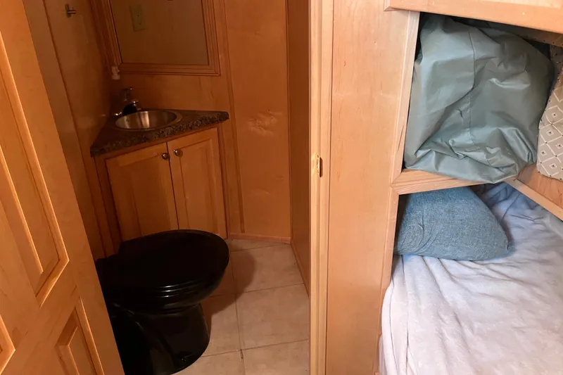 Slide: The Image of Compact 2005 Majestic Legacy RV bathroom with sink, black toilet, and adjacent bunk bed. - 16