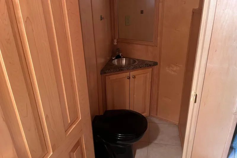 Slide: The Image of Compact wooden bathroom in 2005 Majestic Legacy RV with sink and black toilet. - 17