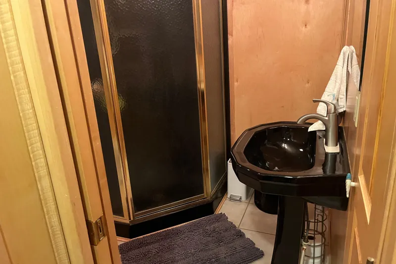 Slide: The Image of Compact bathroom with black sink, gold-trimmed shower, and wooden walls in a 2005 Majestic Legacy. - 26