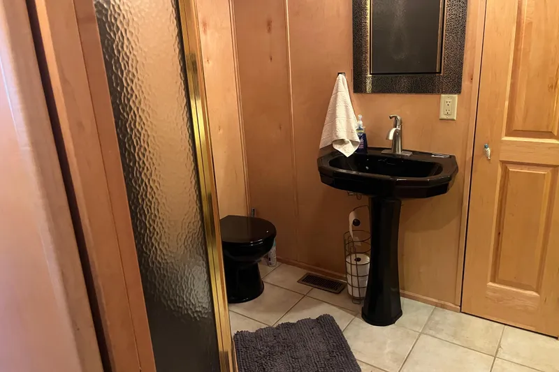 Slide: The Image of Compact bathroom with black fixtures, wooden walls, and a glass shower door in a 2005 Majestic Legacy. - 27