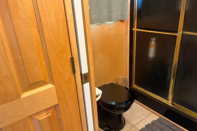 Slide: The Image of Small bathroom with black toilet and shower, wooden door, and tiled floor in a 2005 Majestic Legacy. - 30