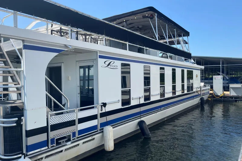 Slide: The Image of 2005 Majestic Legacy houseboat docked, featuring sleek design and spacious upper deck. - 48