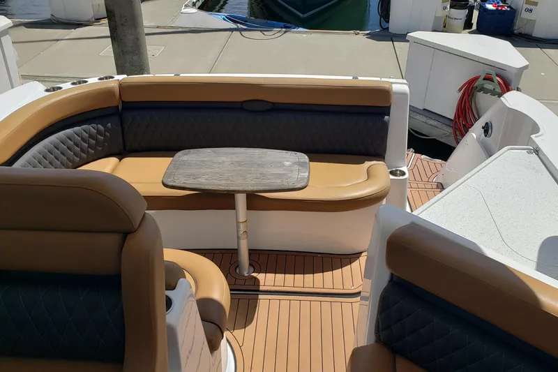 Slide: The Image of 2019 Rinker EX 370 boat interior with tan and gray seating, wooden table, docked at marina. - 19