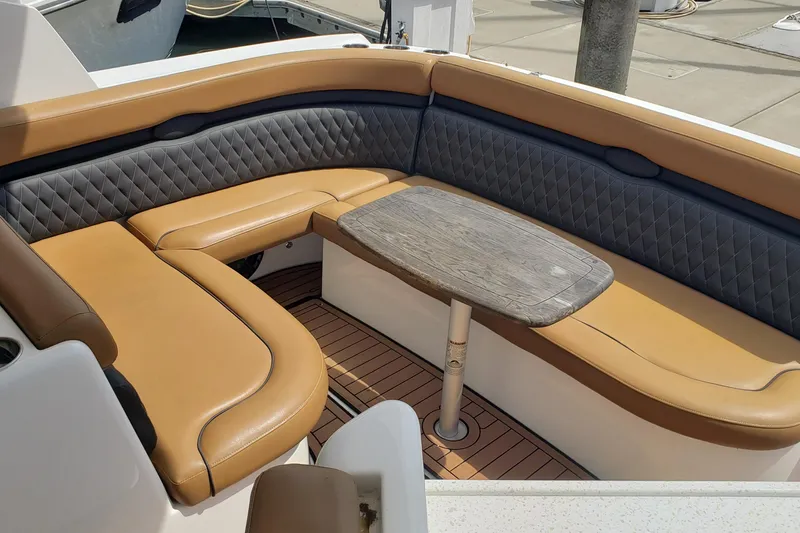 Slide: The Image of 2019 Rinker EX 370 boat interior with tan and gray seating, wooden table, and deck. - 20