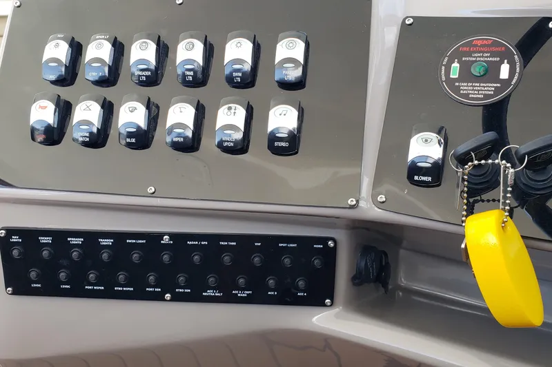 Slide: The Image of Control panel of a 2019 Rinker EX 370 boat with labeled switches and keychain. - 27