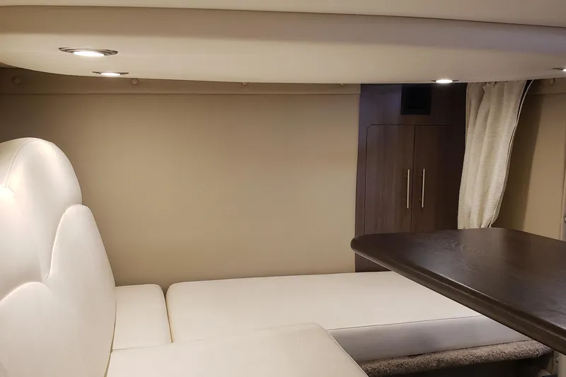 Slide: The Image of 2019 Rinker EX 370 cabin interior with white seating and wooden table. - 40