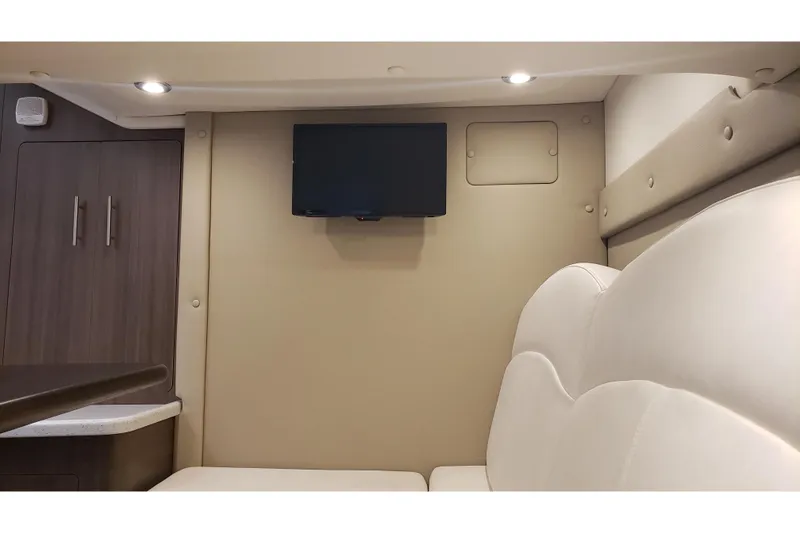 Slide: The Image of 2019 Rinker EX 370 cabin interior with TV, beige seating, and wooden cabinetry. - 43