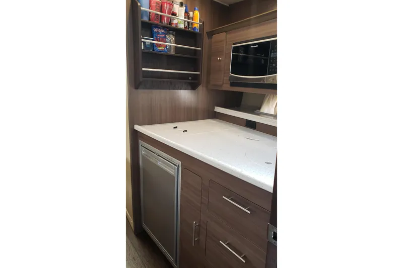 Slide: The Image of 2019 Rinker EX 370 yacht kitchen with modern cabinetry, microwave, and compact fridge. - 47