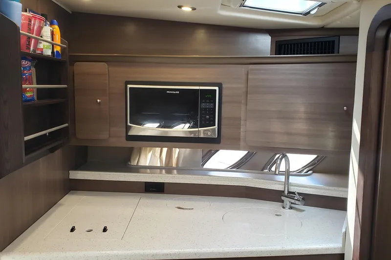Slide: The Image of 2019 Rinker EX 370 yacht kitchen with microwave, sink, and storage shelves. - 48