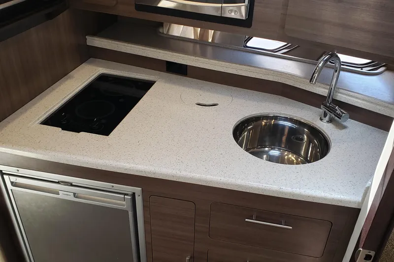 Slide: The Image of 2019 Rinker EX 370 yacht kitchen with sink, stove, and compact fridge. - 49