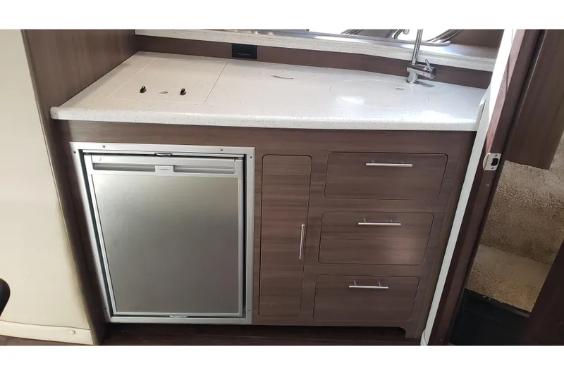 Slide: The Image of 2019 Rinker EX 370 yacht kitchenette with sink, fridge, and wooden cabinetry. - 50