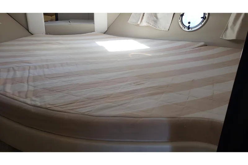 Slide: The Image of 2019 Rinker EX 370 cabin interior with striped bed and porthole window. - 52