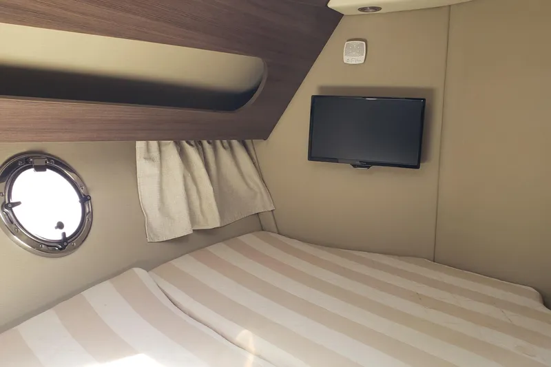 Slide: The Image of 2019 Rinker EX 370 cabin interior with bed, porthole, and wall-mounted TV. - 53