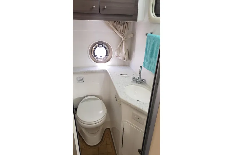 Slide: The Image of Compact bathroom in 2019 Rinker EX 370 boat with sink, toilet, and porthole window. - 56
