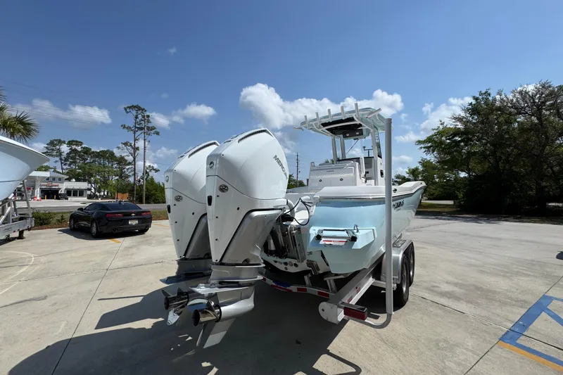 Slide: The Image of 2026 Caymas 291 boat with dual engines on a trailer in a sunny parking lot. - 13