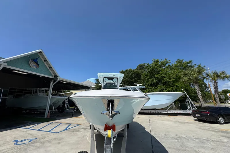Slide: The Image of 2026 Caymas 291 boat on trailer at dealership under clear blue sky. - 6