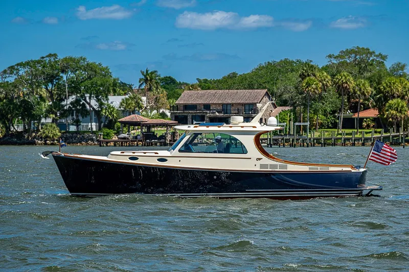 Slide: The Image of 2013 Hinckley Picnic Boat 37 MKIII cruising on a scenic waterway with lush greenery. - 2
