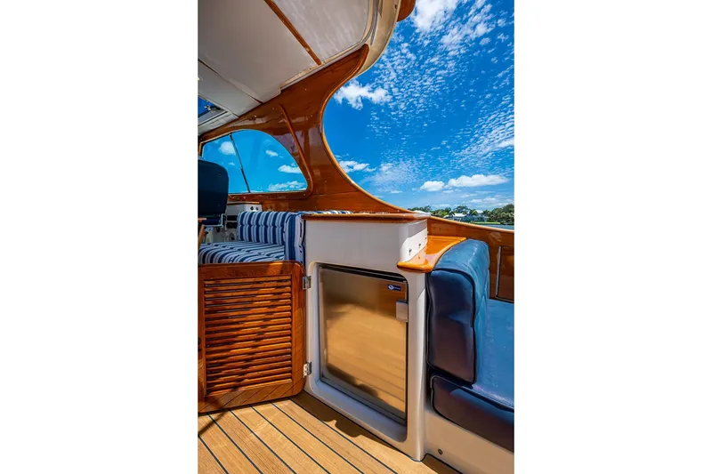 Slide: The Image of 2013 Hinckley Picnic Boat 37 MKIII interior with wooden accents and blue seating under a clear sky. - 8