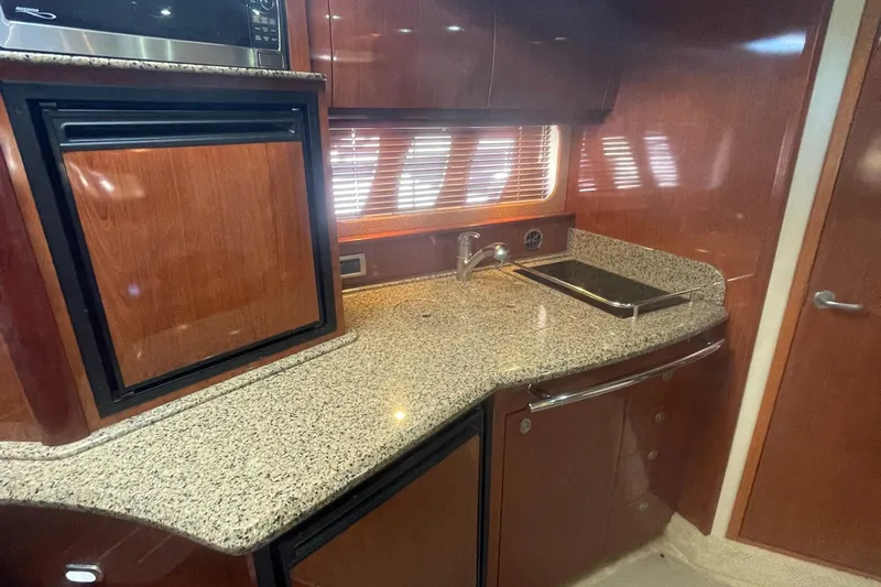Slide: The Image of 2006 Sea Ray 380 Sundancer kitchen with granite countertop, sink, and wooden cabinetry. - 10