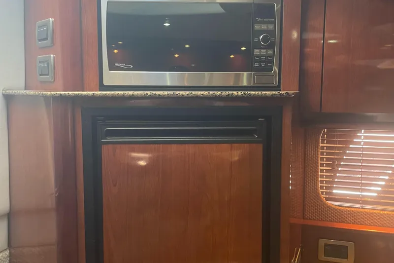 Slide: The Image of 2006 Sea Ray 380 Sundancer interior with microwave and wooden cabinetry. - 11